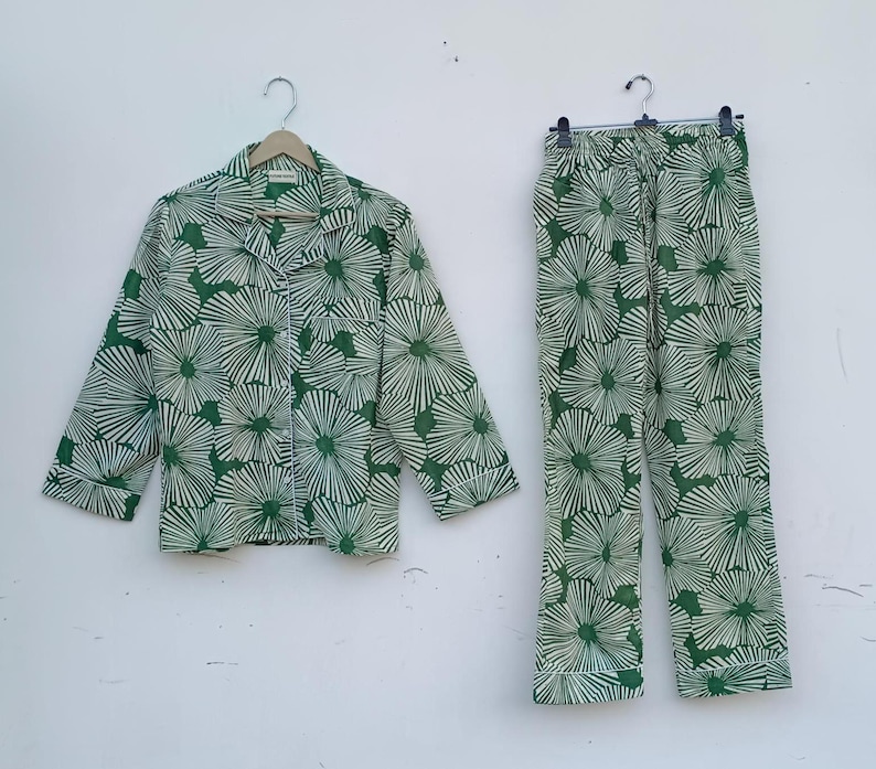 K&ouml;nnte beinhalten: Ein gr&uuml;nes und wei&szlig;es Pyjama-Set mit Blumenmuster. Das Oberteil hat einen Knopfleisten vorne und lange &Auml;rmel. Die Hose hat einen Kordelzugbund und eine gerade Beinpartie.