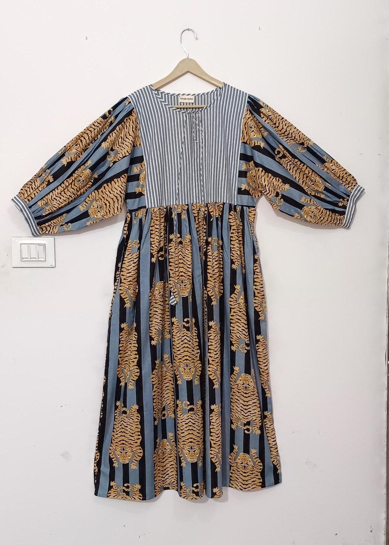 May include: A blue and white striped dress with a tiger print. The dress has a gathered waist and long sleeves with a puffed shoulder.
