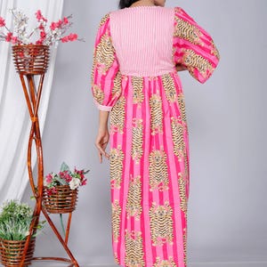 Pu&ograve; includere: Un vestito a righe bianche e rosa con una stampa di tigre. Il vestito ha una vita arricciata e una vestibilit&agrave; ampia. Le maniche sono a sbuffo e terminano al gomito.