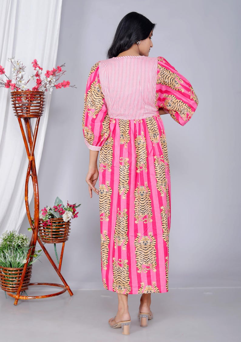 Pu&ograve; includere: Un vestito a righe bianche e rosa con una stampa di tigre. Il vestito ha una vita arricciata e una vestibilit&agrave; ampia. Le maniche sono a sbuffo e terminano al gomito.