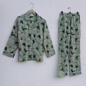 K&ouml;nnte beinhalten: Ein gr&uuml;nes und wei&szlig;es Pyjama-Set mit floralem Muster. Das Oberteil hat einen Knopfleisten vorne und lange &Auml;rmel. Die Hose hat einen elastischen Bund.
