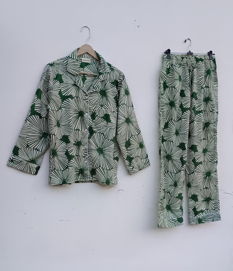 K&ouml;nnte beinhalten: Ein gr&uuml;nes und wei&szlig;es Pyjama-Set mit floralem Muster. Das Oberteil hat einen Knopfleisten vorne und lange &Auml;rmel. Die Hose hat einen elastischen Bund.