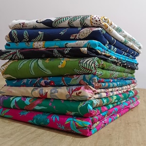 May include: A stack of colorful fabric with various patterns, including floral, animal print, and geometric designs. The fabric is folded neatly and arranged in a pile.