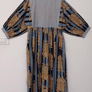 May include: A blue and black striped dress with a tiger print. The dress has a gathered skirt and 3/4 sleeves.