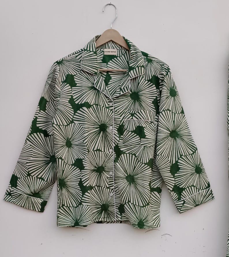 K&ouml;nnte beinhalten: Ein lang&auml;rmliges Hemd in Gr&uuml;n und Wei&szlig; mit einem Blumendruck. Das Hemd hat einen Knopfleisten vorne und eine Tasche auf der linken Seite. Das Etikett auf dem Hemd lautet "Future Textile".