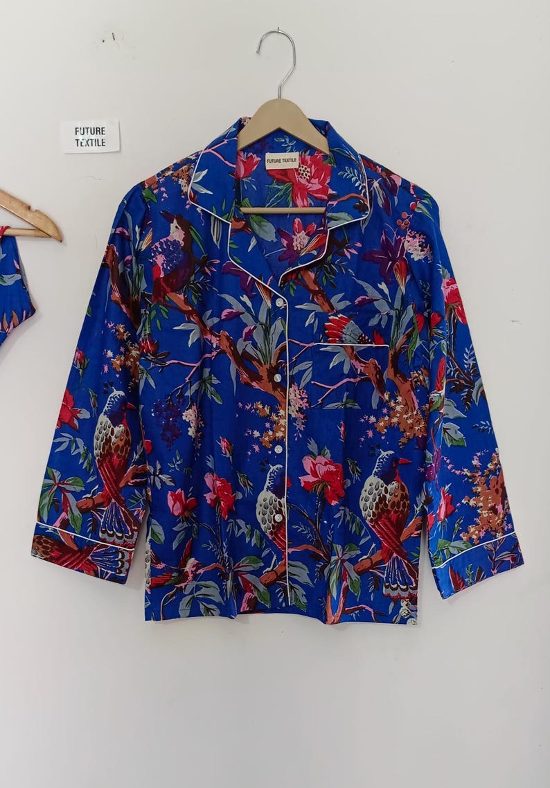 May include: Blue pajama set with a vibrant floral and bird print. The long-sleeved top has white piping and buttons. The text "FUTURE TEXTILE" is visible on a tag.