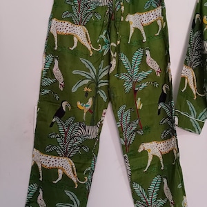 以下が含まれることがあります： ツカン、シマウマ、ヒョウが描かれたジャングル柄の緑色のパジャマパンツです。