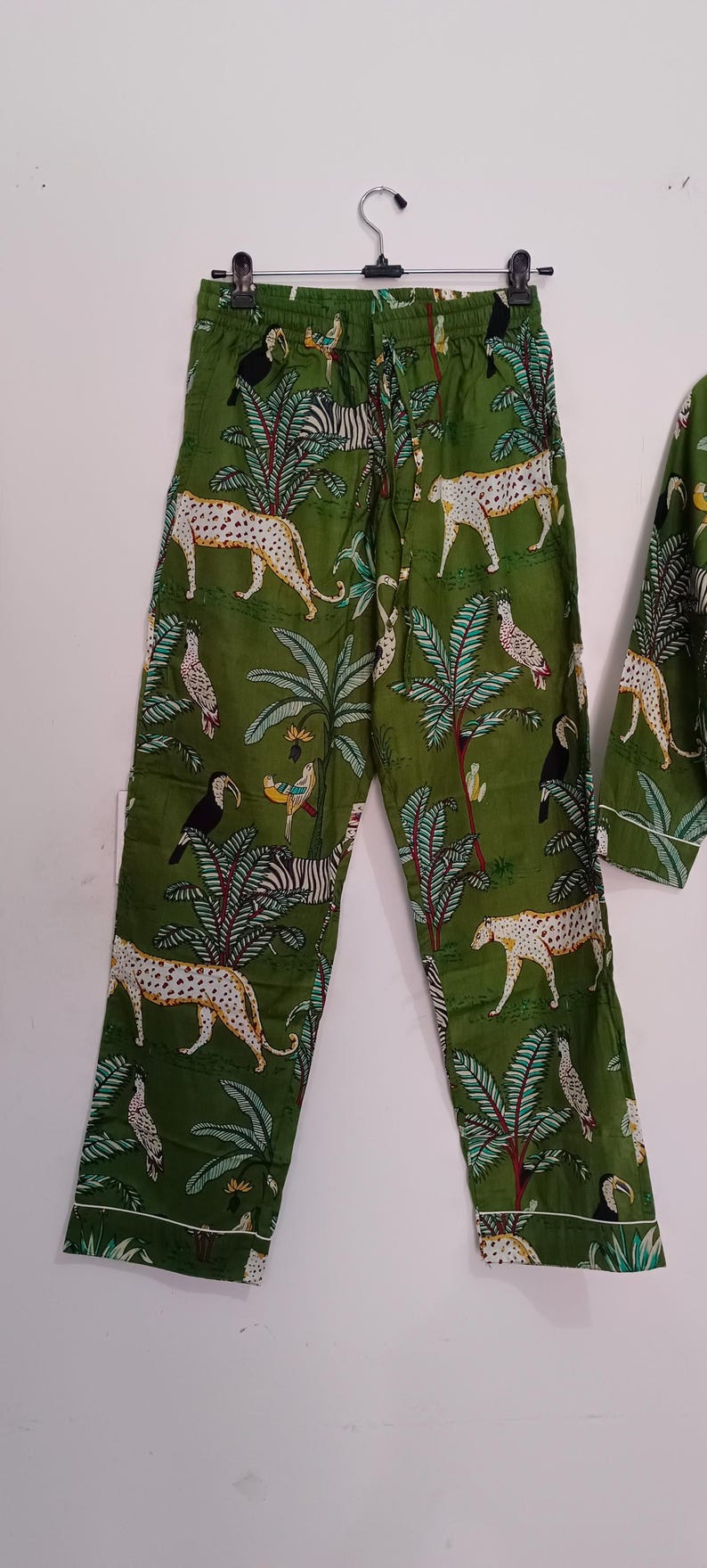 以下が含まれることがあります： ツカン、シマウマ、ヒョウが描かれたジャングル柄の緑色のパジャマパンツです。