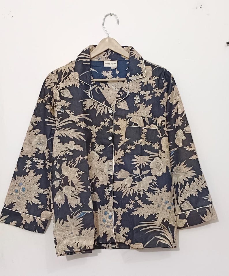 May include: A black button-up shirt with a floral print in beige and blue. The shirt has a collar and long sleeves with a white trim. The label on the shirt reads "FUTURE TEMPLE".