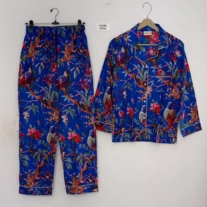 May include: Blue pajama set with a floral and bird pattern. The set includes a button-down shirt and matching pants. The trim is white. The text "FUTURE TEXTILE" is visible on a tag.