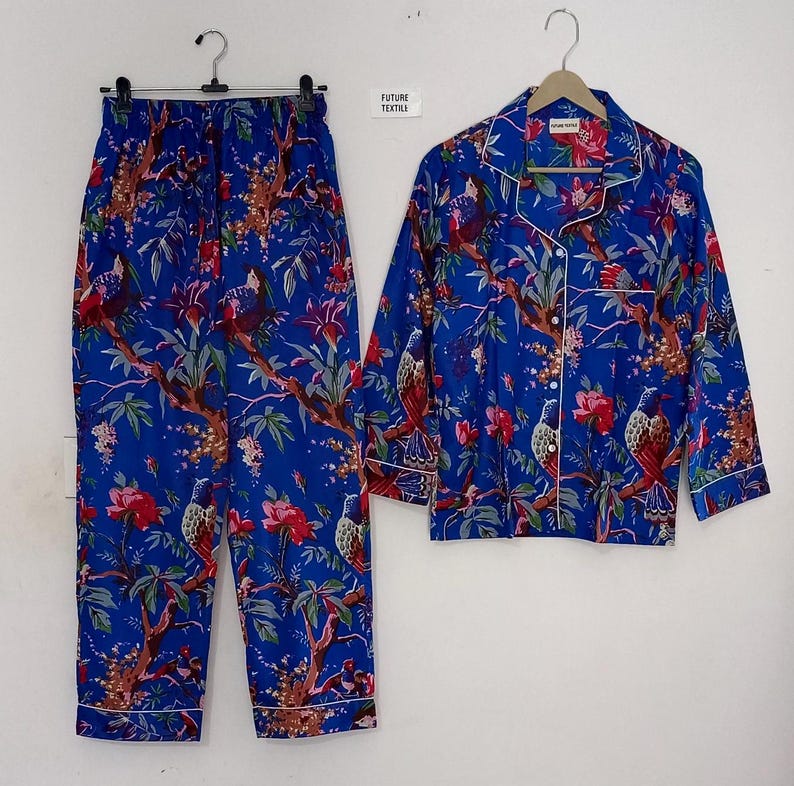 May include: Blue pajama set with a floral and bird pattern. The set includes a button-down shirt and matching pants. The trim is white. The text "FUTURE TEXTILE" is visible on a tag.