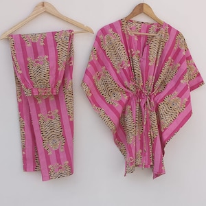 Peut inclure: Pyjama rayé rose et marron avec un imprimé tigre. Le haut est de style kaftan ample avec une taille à cordon. Le pantalon est droit.