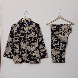 May include: A black and beige pajama set with a floral print. The top has a button-up front and long sleeves. The pants are long and have a straight leg.