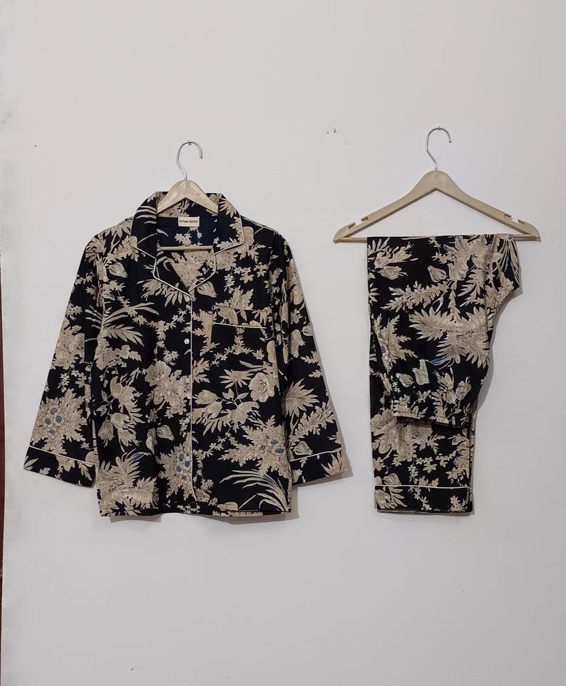 May include: A black and beige pajama set with a floral print. The top has a button-up front and long sleeves. The pants are long and have a straight leg.