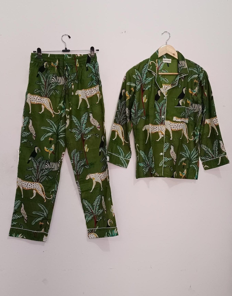 以下が含まれることがあります： 緑色のジャングル柄のパジャマセット。ヒョウ、オニオオハシ、ヤシの木が描かれています。セットには、ボタンダウンカラーの長袖シャツと、それに合わせたパンツが含まれています。