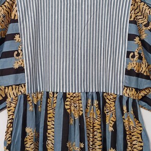 May include: A blue and black striped dress with a white stripe, featuring a pattern of yellow tigers on the skirt.