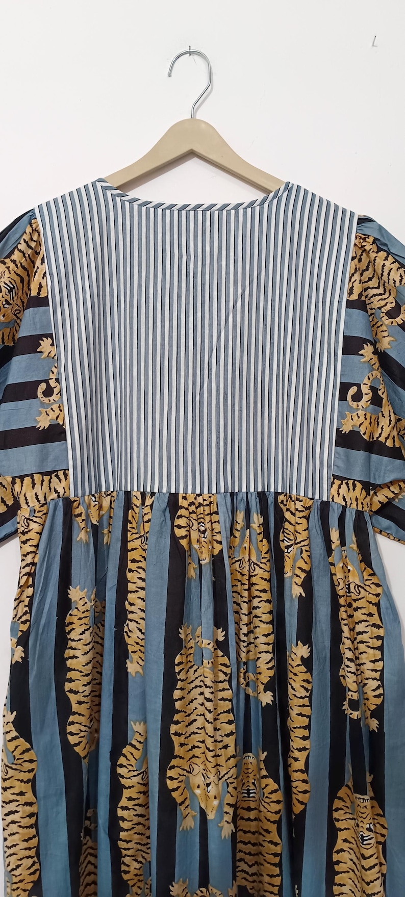 May include: A blue and black striped dress with a white stripe, featuring a pattern of yellow tigers on the skirt.