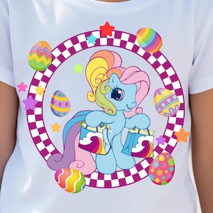 May include: A light blue pony with a rainbow mane and tail holds two shopping bags with clouds and rainbows on them. The pony is surrounded by colorful Easter eggs and stars in a purple and white checkered circle.