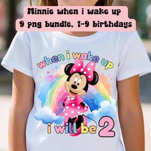 May include: A white t-shirt featuring a colourful rainbow, clouds, and a cartoon image of Minnie Mouse. The text "when i wake up" and "i will be 2" is printed on the shirt.