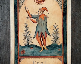 May include: A rectangular tarot card featuring a jester in a blue and orange tunic standing in a landscape under a sun. The card displays the text "FooL" and "Speak as if it is already decided." The illustration uses muted tones of blue, orange, and cream.