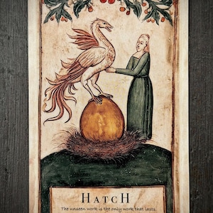 Peut inclure: Une carte rectangulaire illustrée dans un style médiéval montrant une personne en robe verte à côté d'un grand œuf doré dans un nid, surmonté d'un oiseau mythique. Le texte HATCH et The unseen work is the only work that lasts est présent.