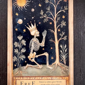 以下が含まれることがあります： 王冠をかぶった骸骨が木の前でひざまずいているタロットカードのイラスト。背景は星が輝く濃い青色の夜空。カードには「FREE」の文字と関連する引用句が下部に表示されています。