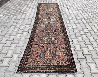 Könnte beinhalten: Ein langer, rechteckiger Teppich mit traditionellem persischem Design. Der Teppich ist in den Farben Rosa, Braun, Blau und Weiß gehalten. Der Teppich hat einen Fransenrand.