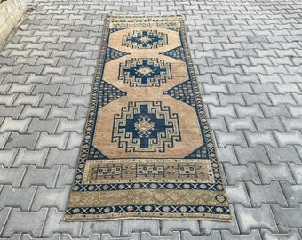 Puede incluir: Una alfombra pasillera rectangular larga con fondo color canela y tres medallones geométricos azul oscuro. La alfombra presenta intrincados patrones de borde en azul marino y motivos repetitivos más pequeños en una disposición simétrica.