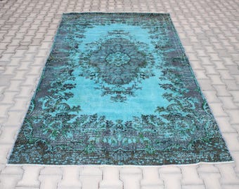 Puede incluir: Una alfombra vintage turquesa y verde oscuro con un patrón floral. La alfombra tiene un aspecto desgastado y es perfecta para añadir un toque de estilo bohemio a cualquier habitación.