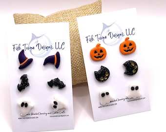 May include: Halloween-themed stud earrings on white cards. Designs include witch hats, bats, jack-o'-lanterns, black cats, and ghosts. The earrings are in black, orange, purple, and white. The cards have the text "Fish Towne Designs, LLC".