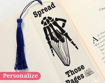 May include: A clear bookmark with a black skeleton hand design and the text "Spread Those Pages". The bookmark has a blue tassel.