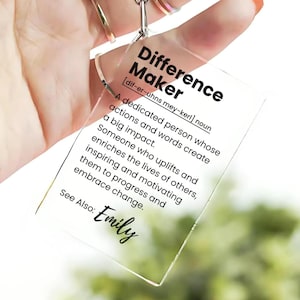 May include: A clear acrylic keychain with the word "Difference Maker" defined as "a dedicated person whose actions and words create a big impact." The keychain also includes the name "Emily".