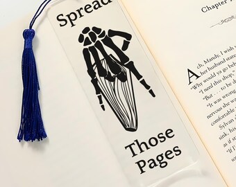 May include: A clear bookmark with a black skeleton hand design and the text "Spread Those Pages".