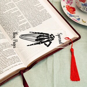 May include: A clear bookmark with a black skeletal hand design and the text "Spread These Pages". The bookmark has a red tassel.