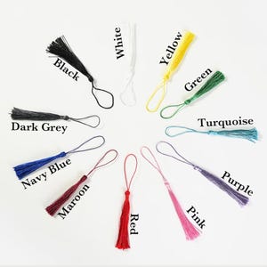 May include: Assortment of 12 colorful tassel keychains in various colors including black, white, yellow, green, turquoise, purple, pink, navy blue, maroon, red, and dark grey.