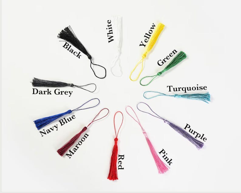 May include: Assortment of 12 colorful tassel keychains in various colors including black, white, yellow, green, turquoise, purple, pink, navy blue, maroon, red, and dark grey.