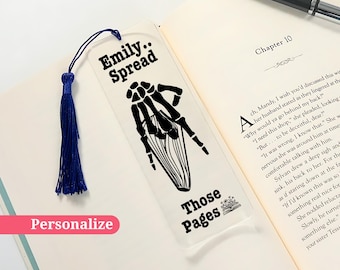 May include: A clear bookmark with a black skeleton hand design and the text "Emily: Spread Those Pages". The bookmark has a blue tassel.