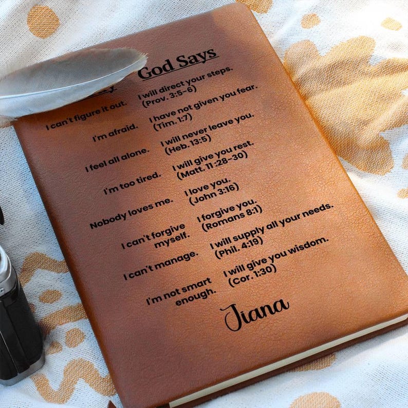 May include: A brown leather journal with the words "God Says" embossed on the front cover. The journal has a list of inspirational quotes with bible verses. The name "Jiana" is written at the bottom of the cover.