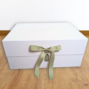 May include: A rectangular white gift box featuring a sage green ribbon tied in a bow at the centre front. The top lid of the box displays the name Sophie in a light-coloured script font. The box has a clean, solid construction with a smooth finish.