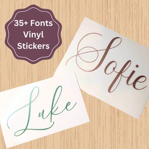 May include: Two white vinyl stickers with names written in cursive script. The sticker on the left says "Luke" in green script. The sticker on the right says "Sofie" in rose gold script.  35+ Fonts Vinyl Stickers.