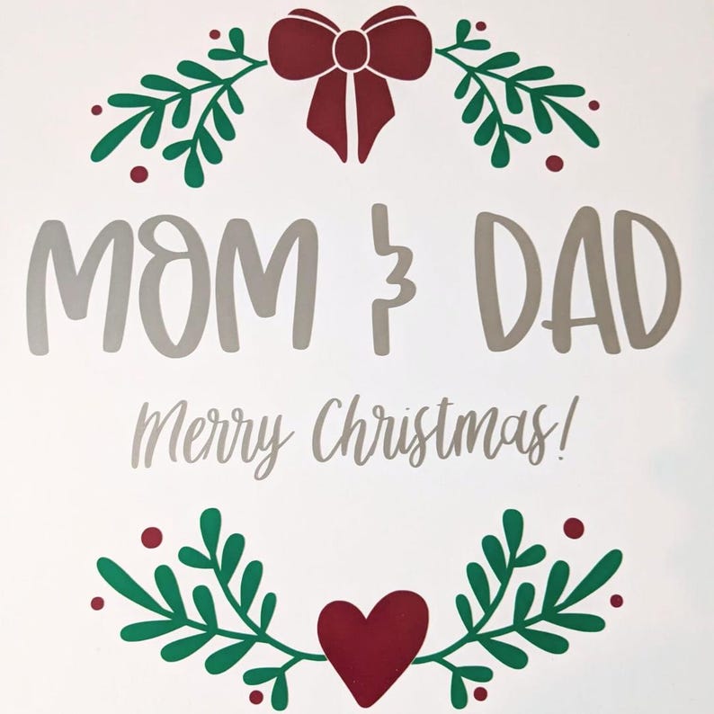 May include: A white background with the words "MOM & DAD" in gray, and "Merry Christmas!" in a script font. The design includes a red bow, green leaves, and a red heart, creating a festive holiday theme.