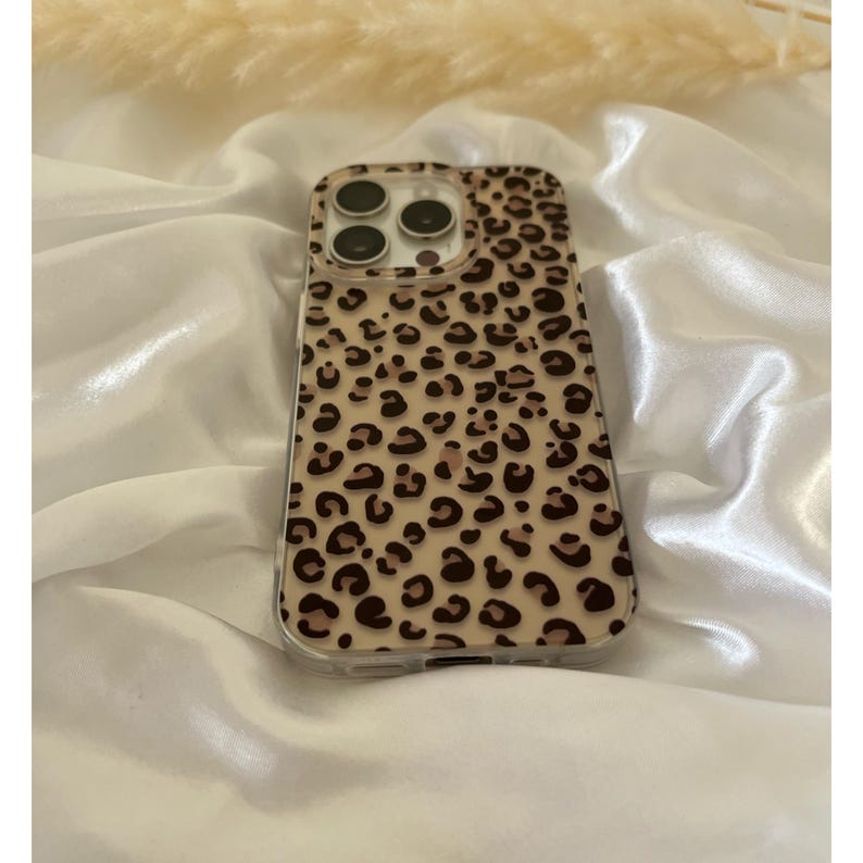 Op de afbeelding: Een transparante telefoonhoes met een luipaardprint. De hoes heeft een verhoogde camerabult en een transparante achterkant.