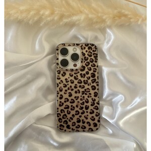 Op de afbeelding: Een transparante telefoonhoes met een luipaardprint. De hoes heeft een verhoogde camerabult met drie zwarte camera-objectieven.