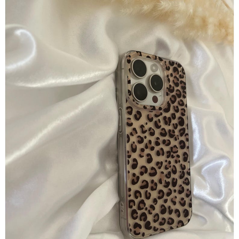 Op de afbeelding: Een transparante telefoonhoes met een luipaardprint. De hoes heeft een verhoogde camerabult met drie zwarte camera-uitsparingen.