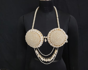 Op de afbeelding: Een witte parel en schelp bh-top met een gelaagde parelketting. De bh-top is gemaakt van witte parels en schelpen, en de ketting is gemaakt van witte parels.
