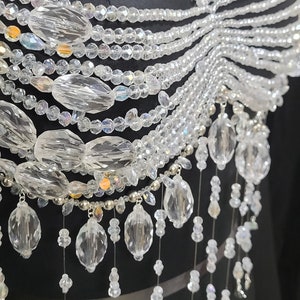 May include: A crystal beaded necklace with a layered design and a cascading fringe of crystal beads.