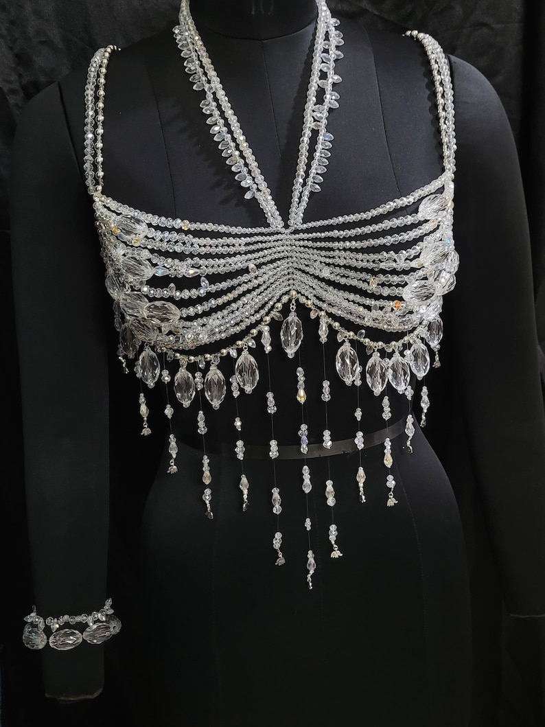 May include: A crystal beaded top with a halter neckline and a fringe design. The top is made of clear beads and has a delicate, feminine look.