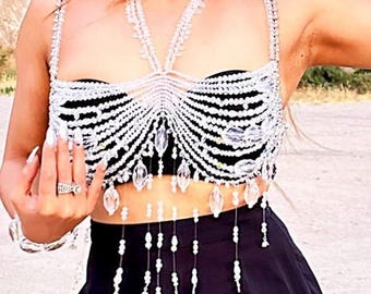 Op de afbeelding: Een wit geperld crop top met een franje onderkant. De top is gemaakt van kleine, heldere kralen en heeft een halternek-stijl.