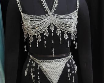 Può includere: Un set di reggiseno e slip in perle di cristallo con un top halter e un fondo a triangolo. Il set è realizzato con perle trasparenti e ha un aspetto delicato e femminile.