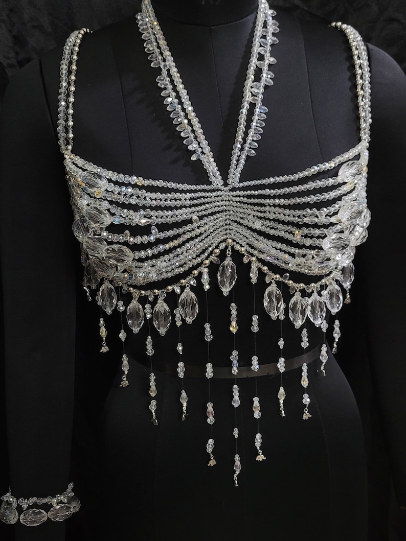 May include: A crystal beaded top with a halter neckline and a fringe bottom. The top is made of clear crystals and has a delicate, feminine look.